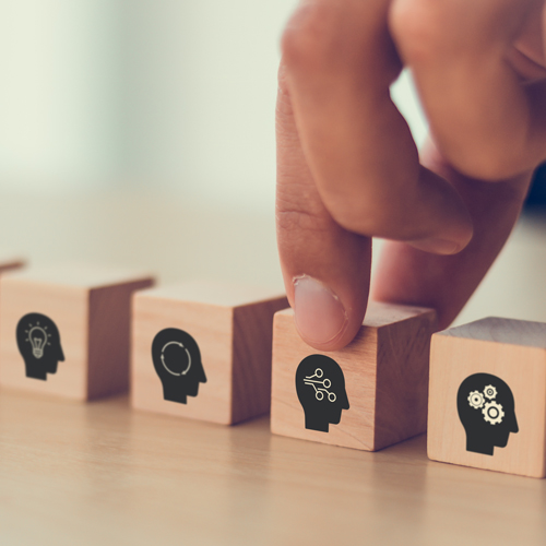 Person grabbing blocks with graphics of heads supposed to represent upskilling and reskilling